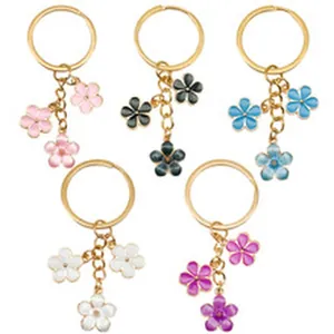 Detailed macro view showing five colorful enamel flower keychains with gold metal rings