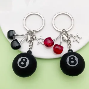 Detail shot of cherry and 8-ball resin keychains on a clean white and green background.