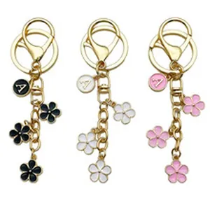 Close-up of floral alloy keychains in black, white, and pink with letter A charms.