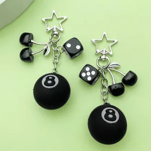 Detailed view of black cherry and 8-ball resin charms on a star-shaped metal keychain