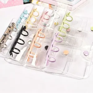 Close-up view of mini 3-hole clear PVC binders with colorful metal rings for photocard storage