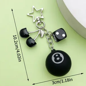 Detail view of a black 8-ball and cherry resin keychain with star clasp, length 10.2cm.