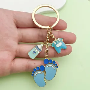 Close-up of a cute blue baby-themed enamel keychain with bottle and footprint charms