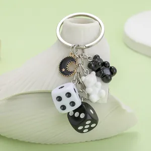 Close-up detail of black and white resin gummy bear and dice charms on a keychain