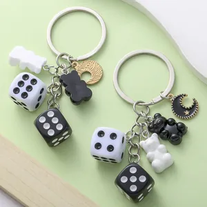 Close-up of resin gummy bear and dice charms on a black and white theme keychain