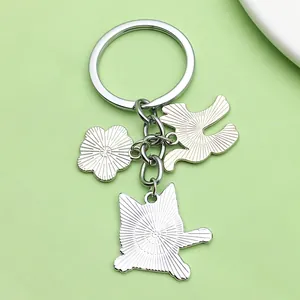 Détail des pendentifs en alliage d'argent chat et fleur sur un anneau de porte-clés.