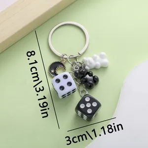 Close-up detail of a resin bear and dice keychain showing accurate size measurements.
