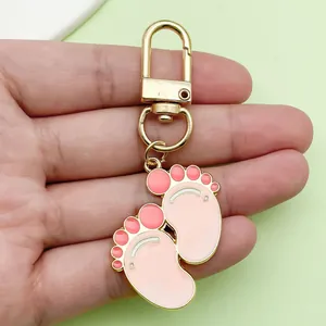 Close-up of cute pink baby footprint alloy drip oil keychain for bags and cars