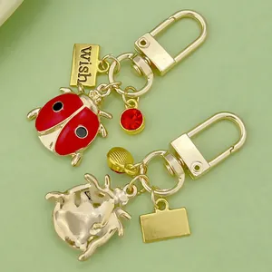 Adorably designed red enamel ladybug keychain with gold U-shape clasp and wish charm