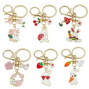 Set of six enamel rabbit keychains with carrot and floral charms on white background