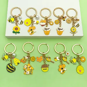 Gros plan de jolis porte-clés en émail avec abeilles, tournesols et pots de miel
