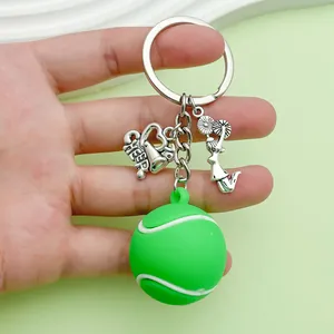 Macro detail of a green PVC tennis ball keychain featuring a metal cheerleader charm.