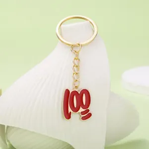 Primer plano de un creativo llavero dorado con un colgante rojo de 100 puntos para bolsos.