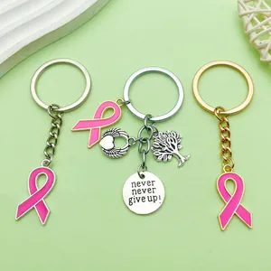 Detalle de llaveros con lazo rosa, árbol de la vida y colgante con grabado motivacional.