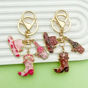 Close-up of pink and brown enamel cowboy hat and boot charms on gold keychains.