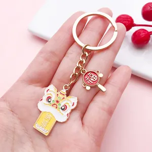 Detail of a Chinese lion dance keychain with traditional lucky charms on a pink background