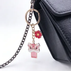 Close-up of Chinese style lion dance keychain with red flower charm on a black bag