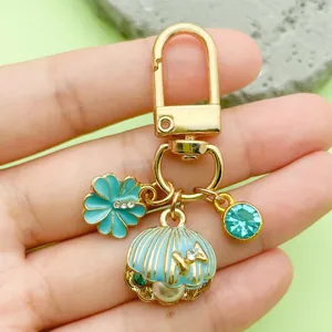 Macro view of a sea-themed gold keychain featuring a blue enamel shell and pearl.