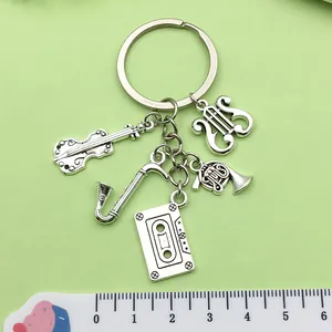 Antique silver music keychain with instrument charms shown next to a measurement ruler