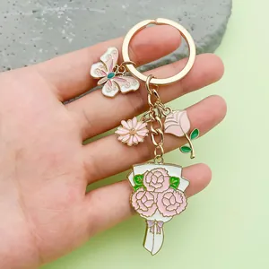 Detail of a pink enamel flower and butterfly keychain held by hand