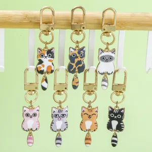 Set mit sieben bunten Emaille-Cartoon-Katzen-Schlüsselanhängern mit beweglichen Schwänzen.