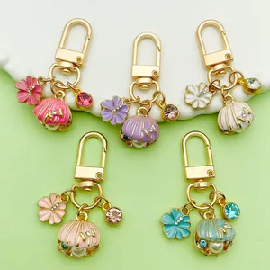 Close-up of five colorful enamel shell and flower keychains with pearls and crystals