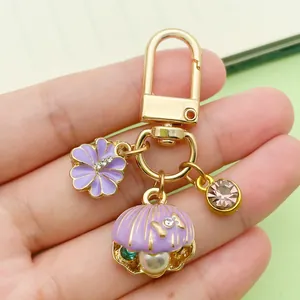 Detailed view of a purple enamel seashell keychain with pearl and floral charms