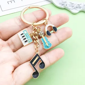 Close-up view of a music-themed alloy keychain featuring piano, guitar, and note charms