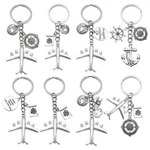 Collectie van acht zilveren metalen sleutelhangers met vliegtuig- en kompasbedeltjes