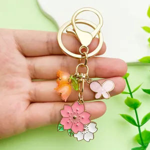 Close-up of a floral metal keychain with pink cherry blossoms and a butterfly charm.