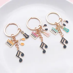 Music-themed alloy keychains featuring piano, guitar, and headphones charms on a white plate.