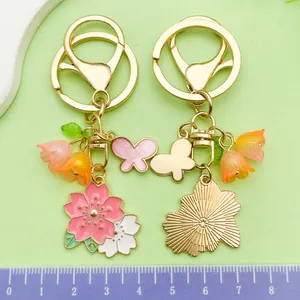 Detailed view of pink floral and butterfly metal keychains with ruler showing 8cm scale