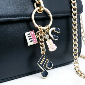 Detail view of musical themed keychain with piano and guitar charms on a black bag