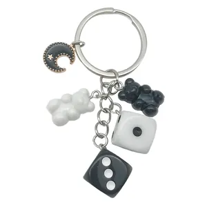 Handmade black and white resin keychain featuring bear, dice, and crescent moon charms