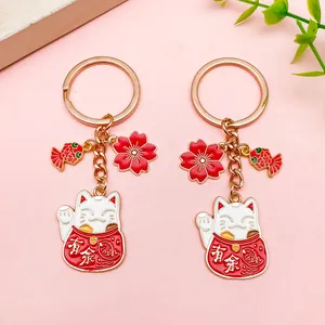Detalle del llavero del gato de la suerte Maneki-neko con dijes de peces koi y flores