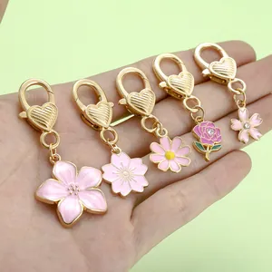 Detailed macro view of five pink enamel floral charms featuring golden heart lobster clasps.