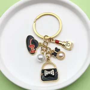 Detalle de llavero dorado con dijes de esmalte que incluyen bolso y lápiz labial