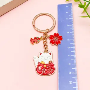 Llavero de gato de la suerte con dijes de sakura y koi mostrado con una regla