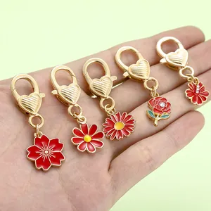 Detail view of 5 vibrant flower-themed lobster clasp charms held in hand for scale reference