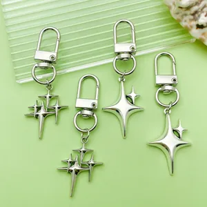 Detail view of four-pointed star metal keychains with polished silver finish on green.