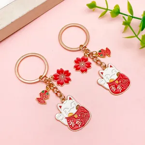 Detalle de dos llaveros de gato de la suerte con dijes de flor de cerezo y pez koi