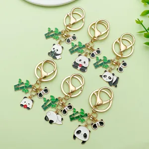 Leuke cartoon panda en bamboe metalen sleutelhangers met emaille op groene achtergrond