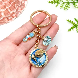 Detailed view of ocean-themed gold-plated keychain with seahorse and shell charms