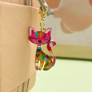 Close-up of a colorful floral alloy cat pendant hanging on a stylish pink bag zipper.