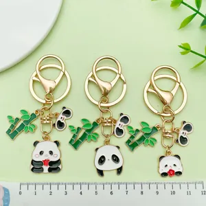 Detailweergave van drie panda- en bamboe-metalen sleutelhangers naast een meetlat.