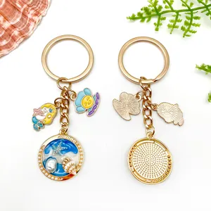 Macro view of gold keychains with detailed ocean charms like shell, starfish, and mermaid