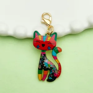 Macro view of a vibrant colorful enamel cat charm featuring a gold lobster clasp for bags
