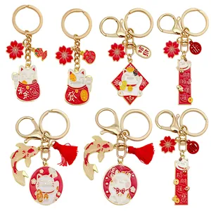 Detalle de llaveros de gato de la suerte Maneki Neko y pez koi con dijes esmaltados