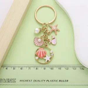 Detail of an ocean-themed alloy keychain with seashell and starfish charms on a green background.