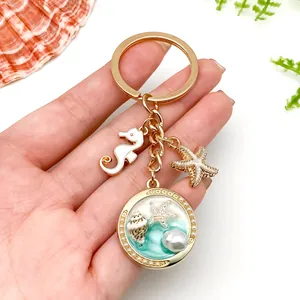 Handheld ocean-themed gold keychain featuring seahorse, starfish charms and resin pearl detail